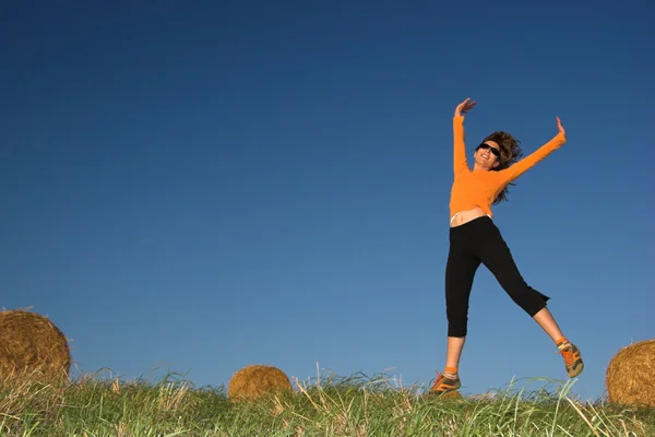 Vrouw springen in een hooi balen veld Stockafbeelding