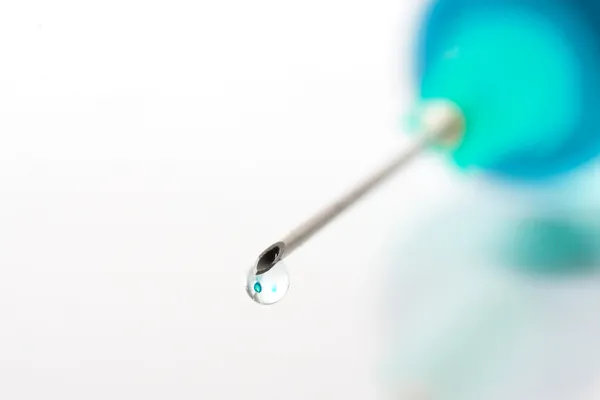 Drop of blue liquid on an injection needle — Stock Photo, Image