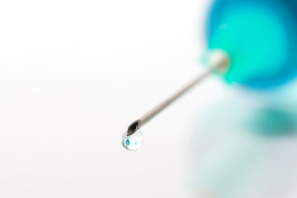 Drop of blue liquid on an injection needle