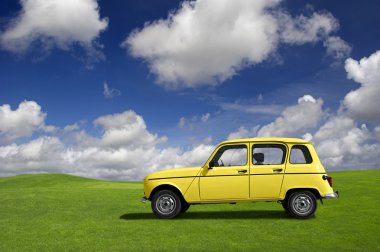 Yellow classic car in a green meadow clipart