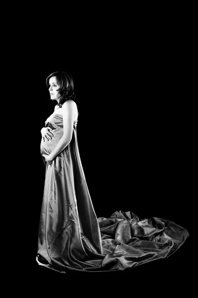 怀孕的女人带来了漂亮的裙子与黑色背景上 — 图库照片