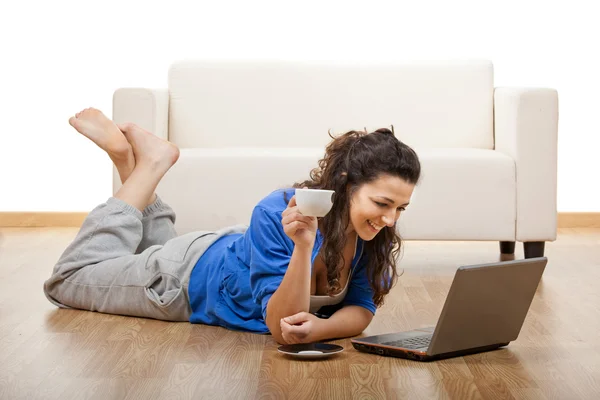 床の上に横たわると コーヒー カップとノート パソコンを使用しての少女の肖像画 — ストック写真
