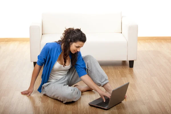 一个女孩坐在地板上 使用笔记本电脑的肖像 — 图库照片