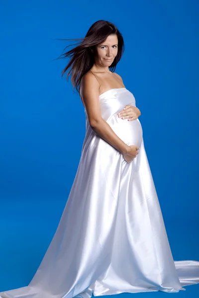 Schöne schwangere Frau posiert vor blauem Hintergrund — Stockfoto