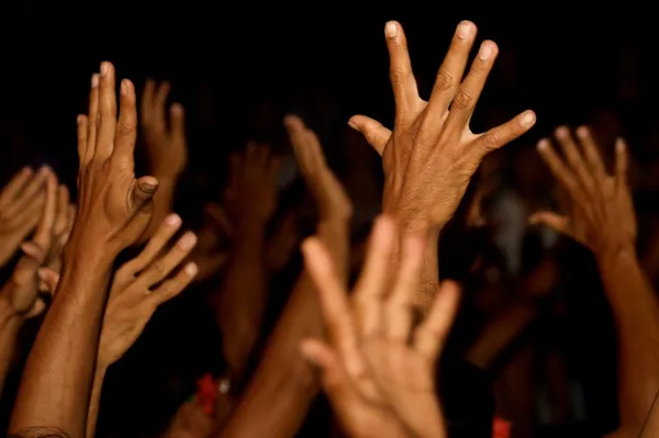 Raised hands on black background — Stock Photo, Image