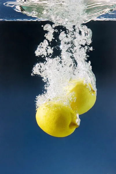 Paar Zitronen in blaues Wasser getaucht — Stockfoto