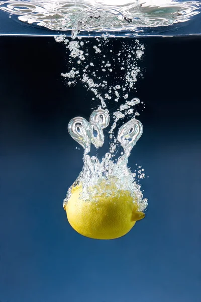 Citron försänkt i blått vatten — Stockfoto