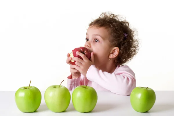 Klein meisje in een rode appel eten — Stockfoto