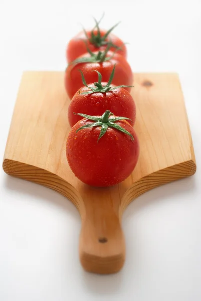 Tomates em tábua de madeira — Fotografia de Stock