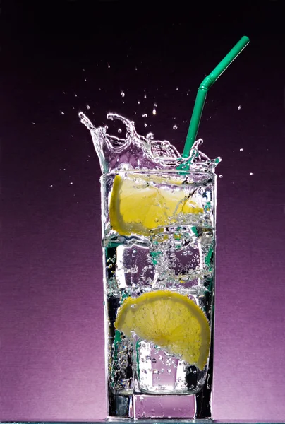 Sliced lemon falling in glass of drink — Stock Photo, Image