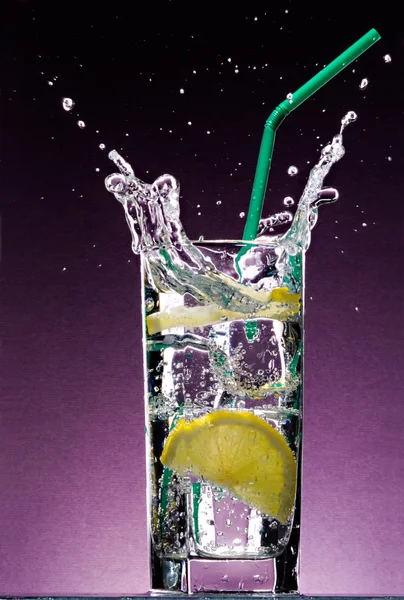 Limão fatiado caindo em copo de bebida — Fotografia de Stock
