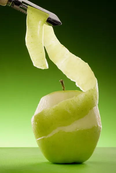 Geschälter grüner Apfel und Schäler Stockbild