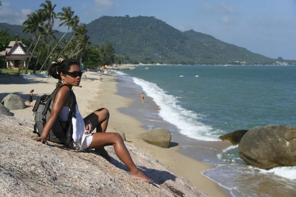 Frau mit Rucksack sitzt auf Felsen lamai beach ko samui thailand — Stockfoto