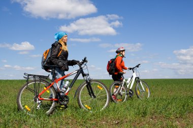 Two girls on bicycles in the countryside. clipart
