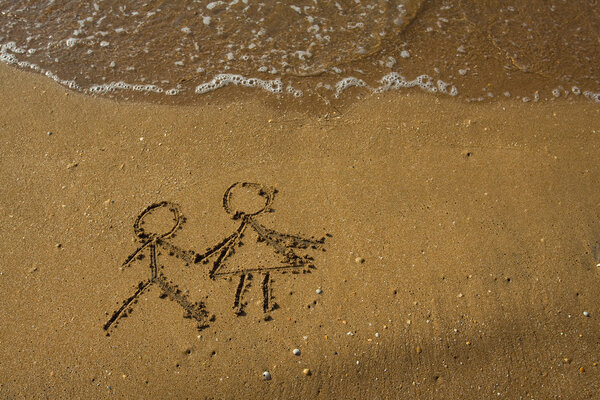 Girl and boy drawn on a beach sand.