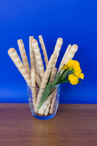 Vidrio con palitos de pan y flor — Foto de Stock