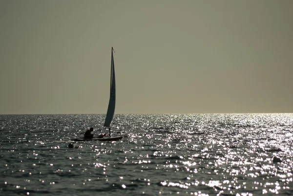 Small sailboat on calm sea at sunset — Stock Photo, Image