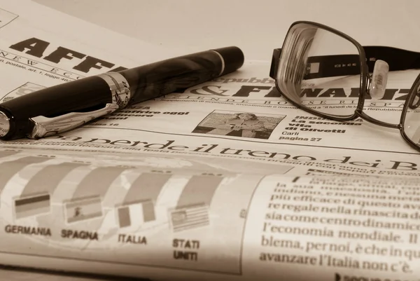 Glassess y pluma en el periódico financiero — Foto de Stock