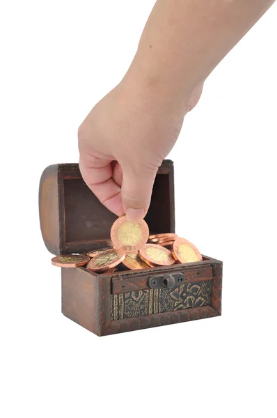 Рука и монеты в сундуке — стоковое фото
