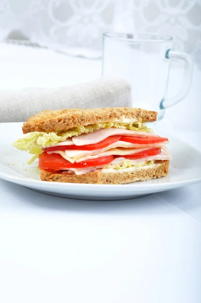 Sandwich de club clásico fresco y delicioso sobre un plato de vidrio blanco con vidrio — Foto de Stock