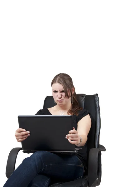 Jeune femme assise sur une chaise et est en colère sur un ordinateur portable Photos De Stock Libres De Droits