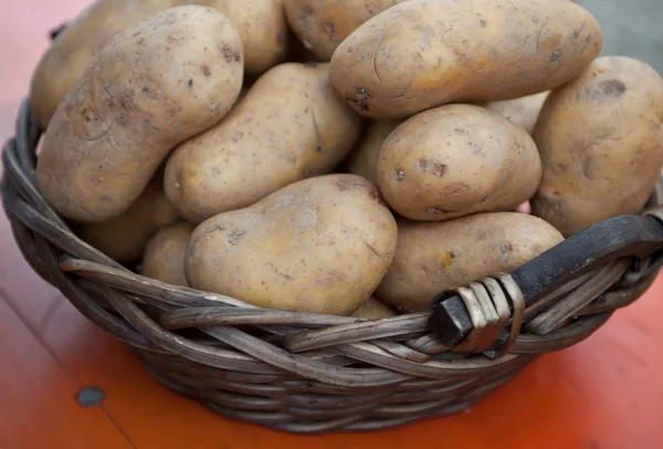 Сырой картофель в плетеной корзине на столе — стоковое фото