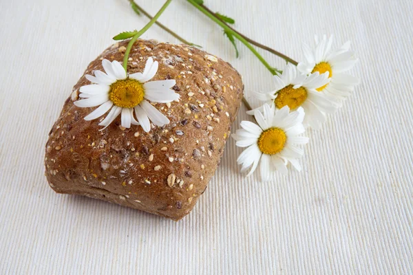 Rollo de pan de centeno fresco y flores de manzanilla —  Fotos de Stock