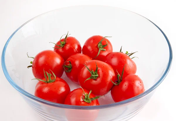 Tomates em uma tigela de vidro em um fundo branco — Fotografia de Stock