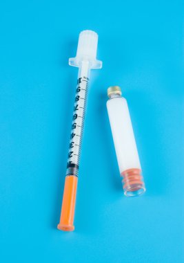 Insulin and syringe on a blue background clipart