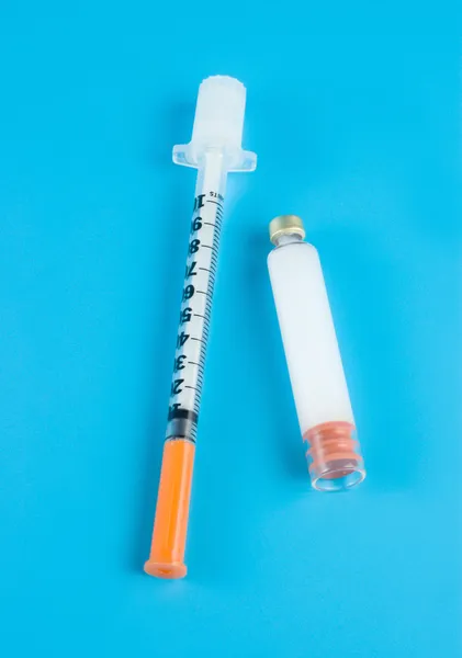 Инсулин и шприц на синем фоне — стоковое фото