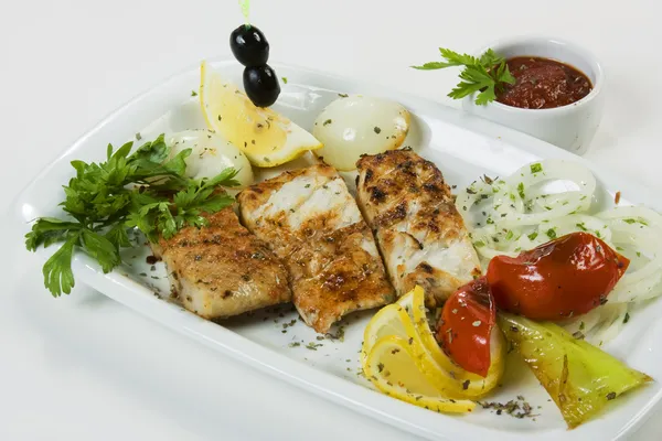 Gegrillter Fisch mit Gemüse und Kräutern auf einem Teller — Stockfoto