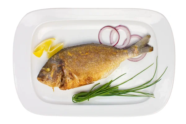 Pesce alla griglia su un piatto con cipolle e limone — Foto Stock