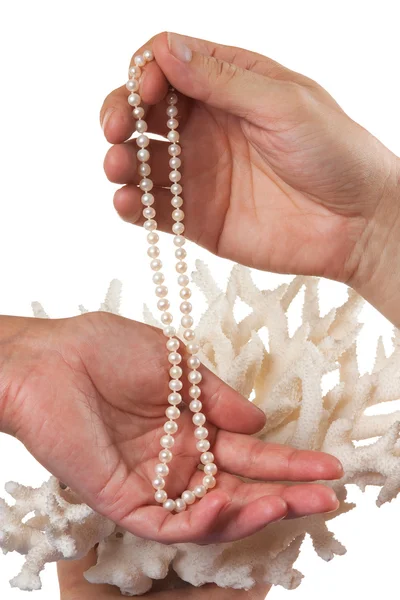 サンゴを背景に彼女の手で真珠のネックレス — ストック写真