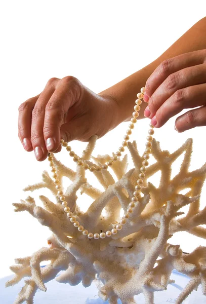 Un collar de perlas en sus manos contra el fondo de coral —  Fotos de Stock