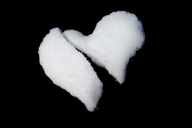 Broken heart made of snow isolated on black clipart