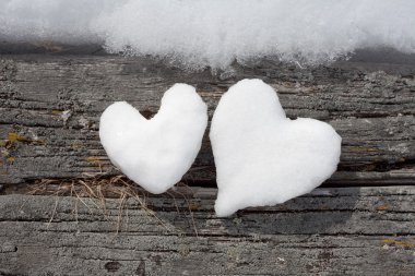 Two snow hearts on weathered wood