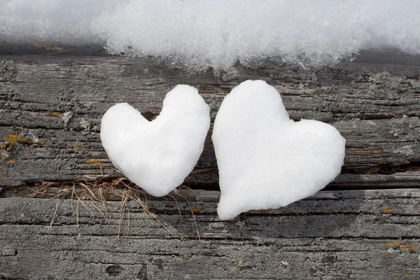 Två snö hjärtan på väderbitna trä — Stockfoto