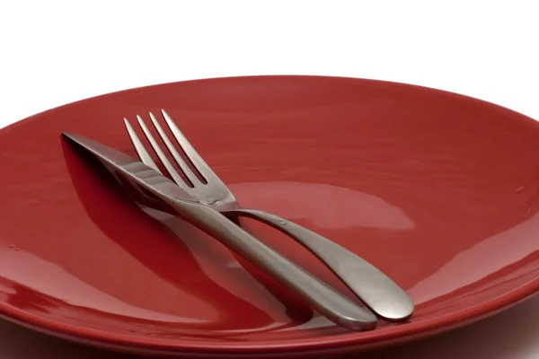 Faca e garfo em placa brilhante vermelho — Fotografia de Stock