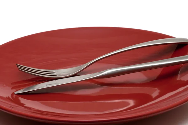 Messer und Gabel auf rotem, glänzenden Teller — Stockfoto
