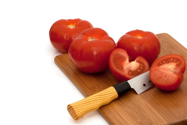 Tomates tranchées et entières et couteau sur planche à pain — Photo