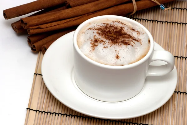 Cappuchino and cinnamon sticks Royalty Free Stock Images