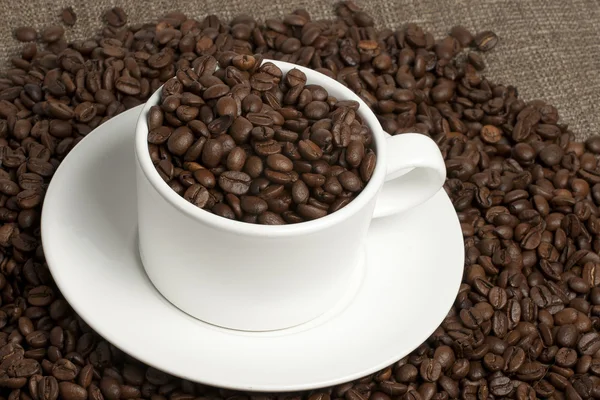 Caneca branca em grãos de café e saques — Fotografia de Stock
