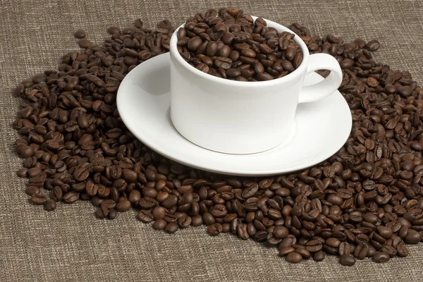 Білий кухоль на кавових зернах і мішок — стокове фото