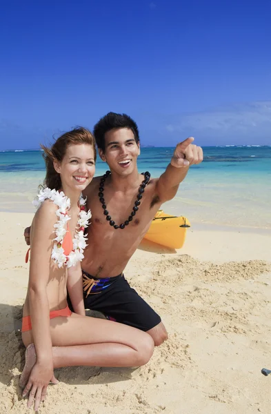 Couple on the beach in hawaii pointing — Stock Photo, Image