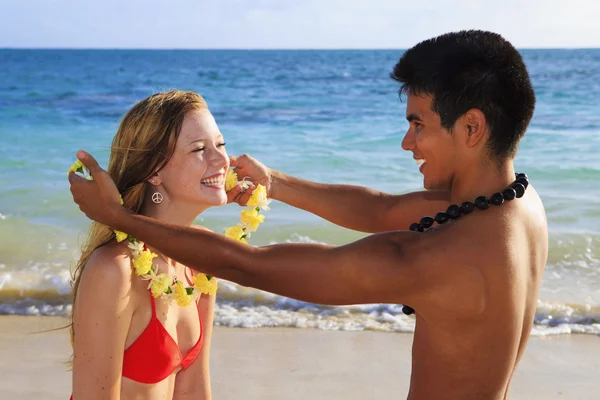 Beachboy ger en blomma lei till en flicka — Stockfoto