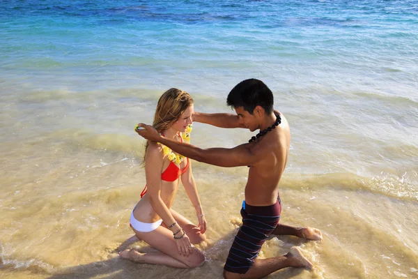 Beachboy geeft een bloem lei aan een meisje — Stockfoto