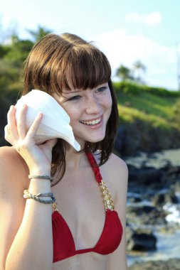 Girl in bikini listening to sea shell clipart