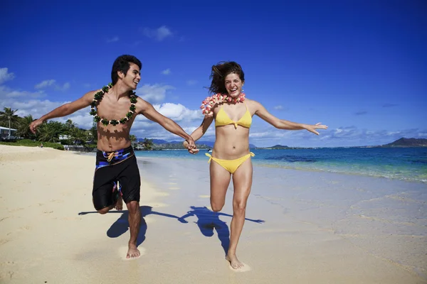 Unga par som springer på stranden — Stockfoto