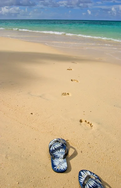 Sandalen und Fußabdrücke am Ufer — Stockfoto