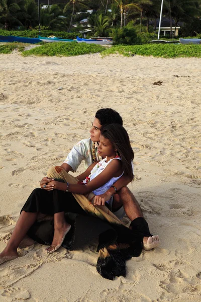 砂の上に座っている若い混血カップル — ストック写真
